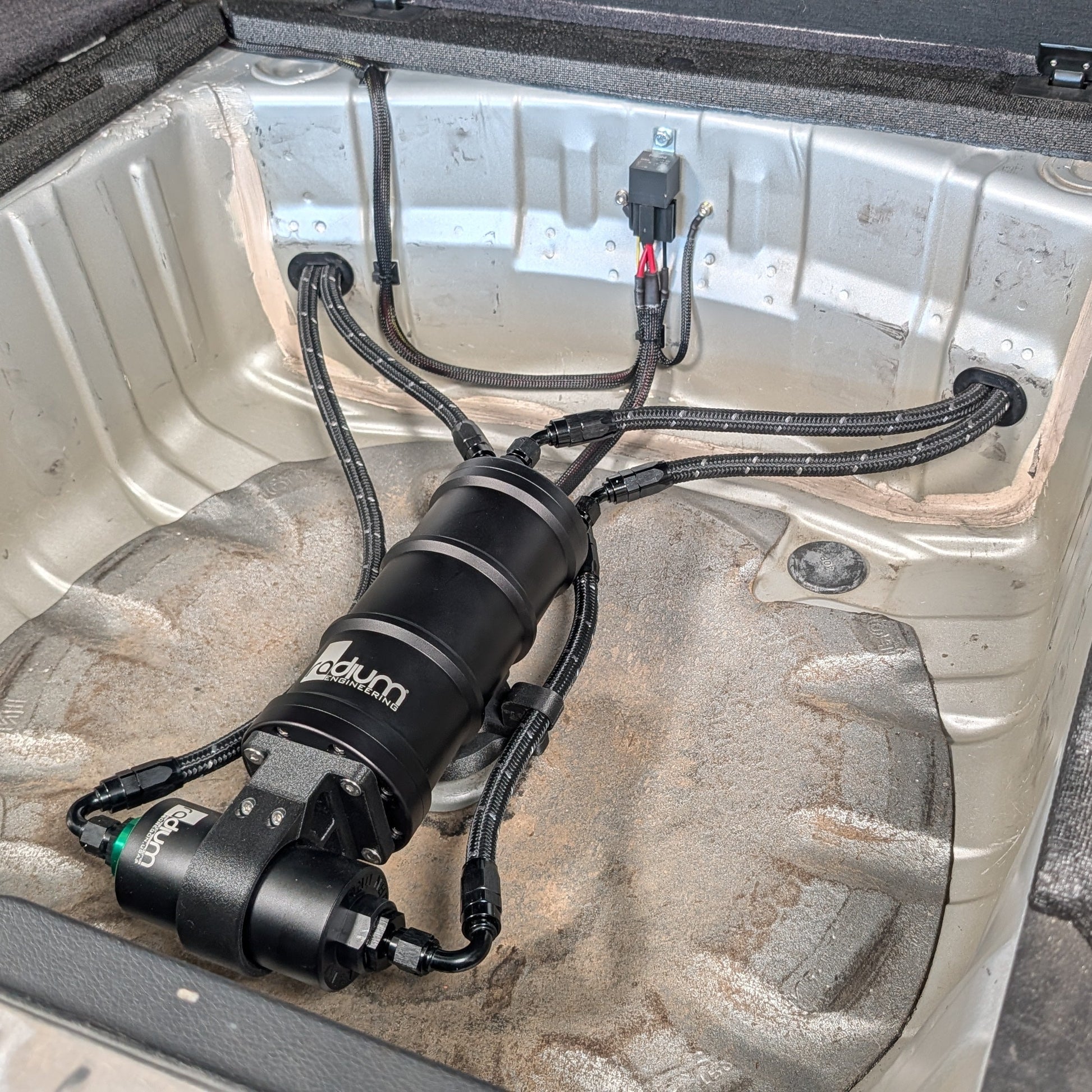 Radium Surge Tank and Fuel Filter Mounted in the Spare Tire Well of a Subaru Side View